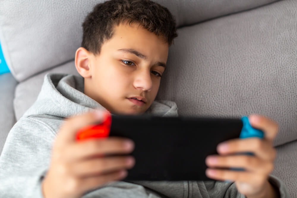 Boy,Plays,Video,Games,On,A,Portable,Console,While,Lying