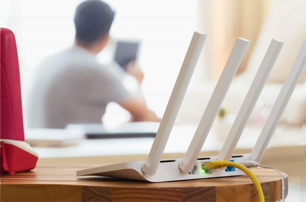 Closeup,Of,A,Wireless,Router,And,A,Man,Using,Smartphone